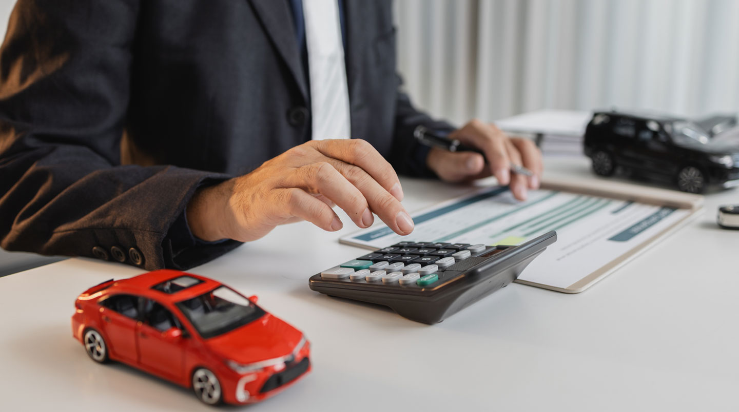 Mains tenant contrat de location automobile imprimé en français avec clauses visibles surlignées en jaune, tablette numérique affichant conditions générales pour comparaison sur surface claire